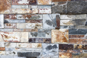 A wall decorated with stones of different colors cut in different sizes and angles