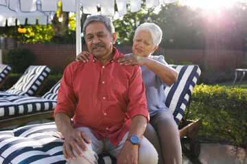 Senior diverse couple enjoying in garden relaxation, woman giving man shoulder massage