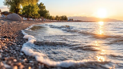 A scenic beach featuring numerous rocks along the shoreline, with clear blue water gently lapping against them, creating a tranquil atmosphere.