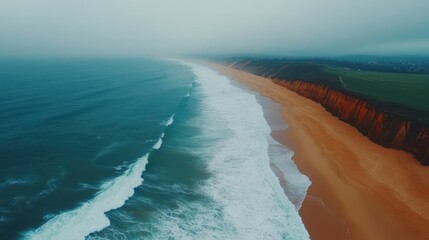 Naklejka premium Aerial view of a tranquil beach featuring a vast expanse of soft, golden sand meeting the gentle waves of a sparkling blue ocean.