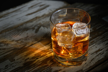 Elegant glass of whiskey on rustic wooden table illuminated by soft lighting