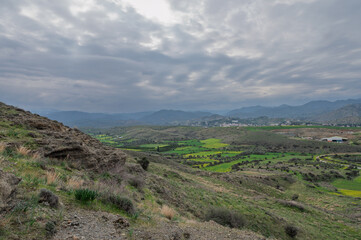 Naklejka premium Lush green valley under dramatic clouds showcases nature's serenity near a quiet mountain town