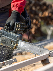 Men sawing using electrical chainsaw at roof construction