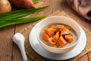 Coconut Milk Stewed orange yam,Thai dessert boiled sliced Sweet Potato in coconut milk with sugar in white bowl.
