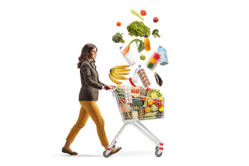 Full length profile shot of a young professional woman walking with falling groceries in a shopping...