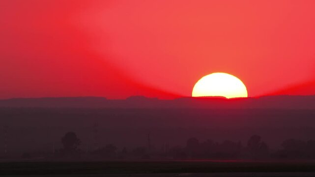 Timelapse, big red sunset twilight with orange and red sky in urban cityscape. Beautiful dramatic big disk sun set