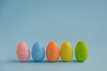 Painted Easter eggs stand on a blue background, horizontal photo. Side view. The concept of the Easter holiday.