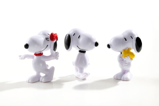 Three Snoopy cartoon character figurines standing on a white background