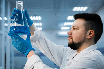 A specialist in a laboratory holds a liquid and analyzes it. The concept: utilizing high-tech...