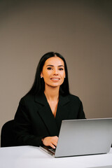 Professional woman working on a laptop in a minimalist office setting during daylight hours