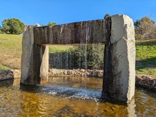 Fuente de agua con forma de puente de piedra en un parque 