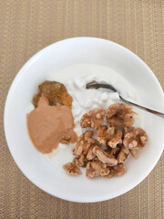 Cottage cheese with walnuts, jam, peanut butter, and spoon in bowl healthy breakfast
