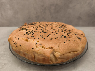 Delicious homemade pie sprinkled with black sesame seeds on glass plate copy space gray background