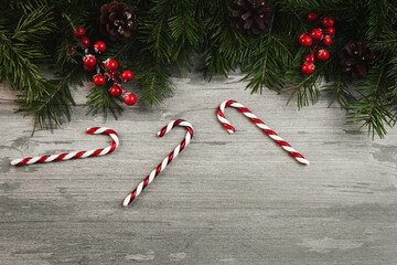 Christmas decorative border with green spruce, cones, holly berries and candy canes on old wooden...
