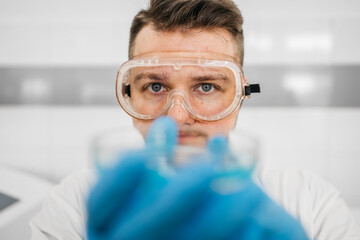 A specialist in a laboratory holds a liquid and analyzes it. The concept: utilizing high-tech...