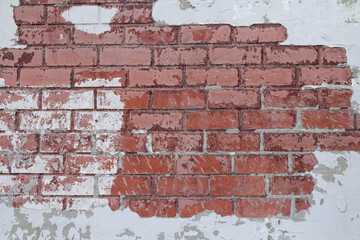 Weathered brick surface with cracked plaster and exposed red bricks