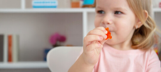 Little girl eating jelly candies or vitamins. Kid.