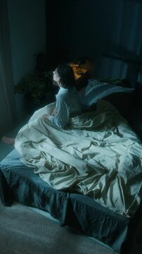 Vertical high angle shot of female sleepwalker waking up in middle of night and walking out of her bedroom