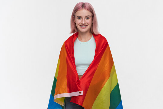 Smiling young hipster girl female student with colorful hair covering with LGBTK rainbow flag showing freedom in love supporting sexual minorities community equal rights for gays lesbians