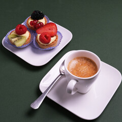 Ravvicinato di una tazzina di caffè sul piattino e un piattino con paste alla frutta