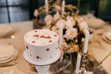 Decor for a gender reveal party in a restaurant with flowers, balloons and cake. Oh baby party