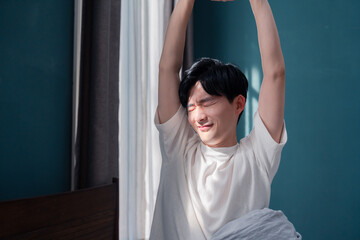 朝日が差し込む中で爽やかに目覚める若い男性