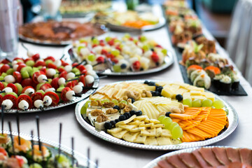 Snacks for the holiday, catering. Various snacks. Assortment of salads, sushi and buffet dishes. Meat, fish, cheese, salads, fruits and vegetables, sauces and canapes for celebrating a festive event.