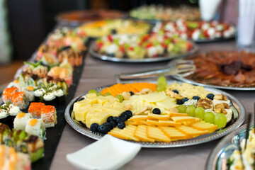 Snacks for the holiday, catering. Various snacks. Assortment of salads, sushi and buffet dishes. Meat, fish, cheese, salads, fruits and vegetables, sauces and canapes for celebrating a festive event.