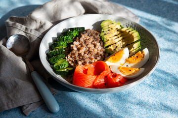 Balanced healthy food on a plate. Buckwheat, boiled egg, cucumber and red fish for breakfast, lunch or dinner.