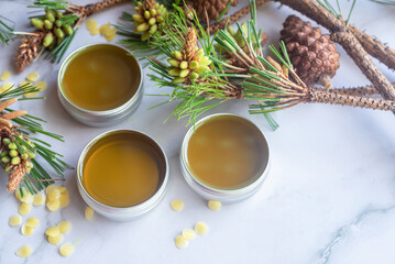freshly poured homemade pine needle salve balm in reusable  tin container on white background.