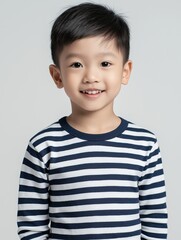 Adorable young boy smiles in a striped shirt.