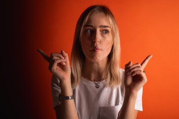 Portrait of a funny young, emotional girl making a fish face, lips and pointing with both hands....