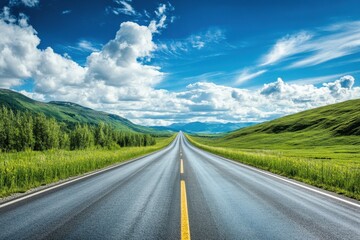 Naklejka premium Stunning long road stretches through green hills under a bright blue sky filled with clouds