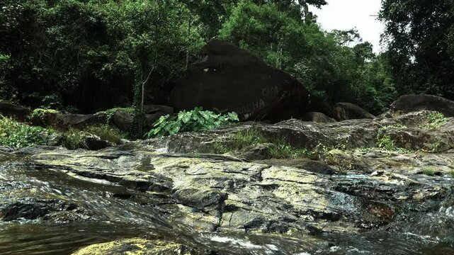 A stream spills over a rocky plateau in the jungle
