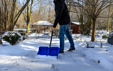 Schnee im Winter zur Sicherheit mit einem Schneeschieber  räumen