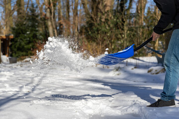 Schnee mit Schneeschieber auf einen Haufen werfen