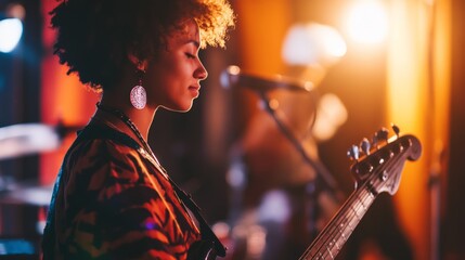 Young african female bass guitarist performing live on stage with vibrant lighting