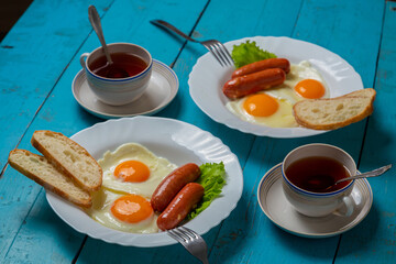 Breakfast for two fried eggs with sausages crispy white bread vegetable salad and tea