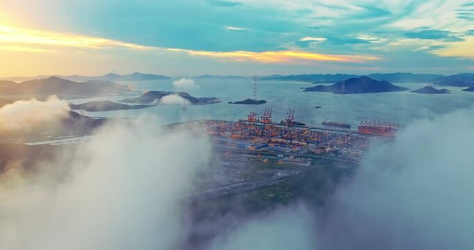 Aerial view of harbor and container terminal with ship and mountain range under twilight sky and coulds