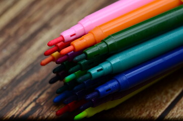 Fototapeta premium A macro shot of an assortment of different colored crayons stacked together isolated on a wooden background.