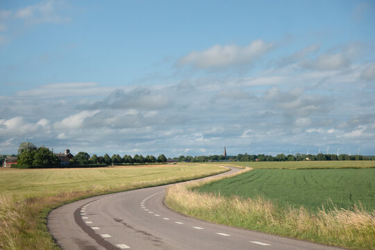 Winding road in agricultural countryside among wheat fields in Scania, Sweden on a clear summer day