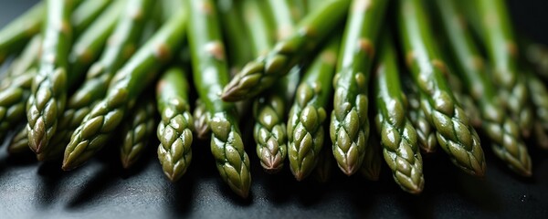 Crisp asparagus tips aligned, fresh water droplets emphasize natural state. Macro photo highlights vivid green hues, organic texture. Healthy diet concept. Spring seasonal vegetable, gourmet cuisine,