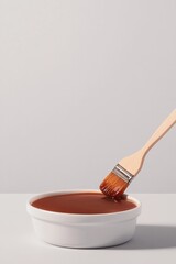 Rich brown sauce in white bowl, gently brushed with wooden utens