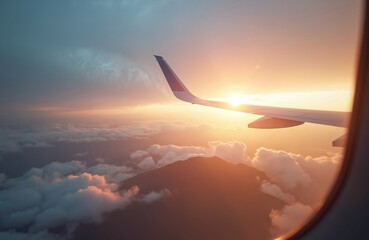 Airplane wing view from plane window over foggy mountains at sunset. Sky and sun above clouds. Scenic flight travel picture. Mountain top below clouds, airline business journey.