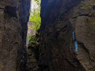 A crevice or corridor in the rock leading through the Niagara Escarpment during summer. Blue markers indicate a left turn on a side trail on the Bruce Trail