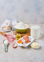 Step-by-step preparation of thin pancakes or crepes on a light background. Prepared ingredients for cooking crepes.