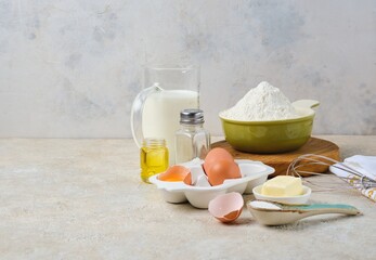 Step-by-step preparation of thin pancakes or crepes on a light background. Prepared ingredients for cooking crepes.