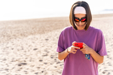 Young woman using smartphone on beach volleyball court