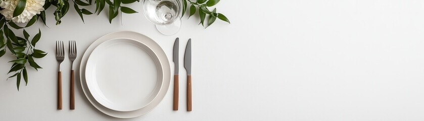 Elegant Dining Table Setting with White Plates and Cutlery Surrounded by Greenery and Floral Accents
