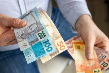 Brazil money. Businessman holding out his hand with Brazilian reais. BRL banknotes. Financial...